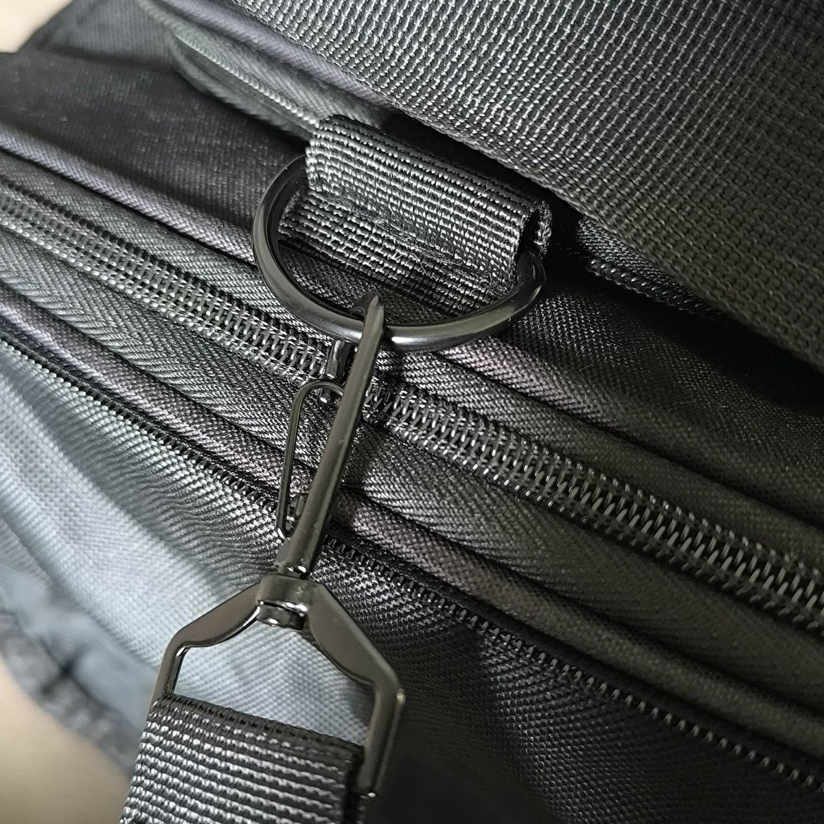 Metalen karabiner van de schouderband aan de D-ring van de tas