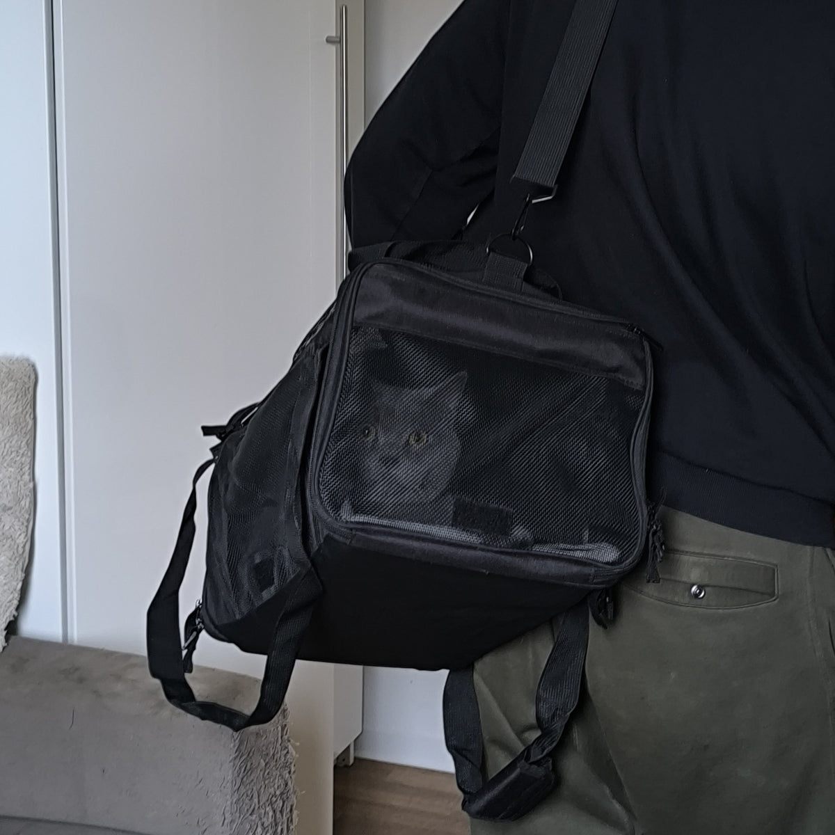 Tas met kat aan de schouderband gedragen, kat zichtbaar achter het gaas